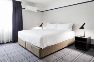 a bedroom with a white bed and a window at Brassey Hotel - Managed by Doma Hotels in Canberra