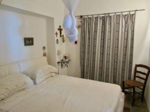 a bedroom with a white bed and a chair at Antico Dammuso Al Tramonto in Pantelleria