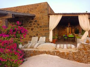 a stone building with a patio with chairs and flowers at Antico Dammuso Al Tramonto in Pantelleria