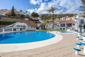 a swimming pool in a villa with palm trees and houses at Plaza Cadiz 4 overlooking Playazo in Nerja