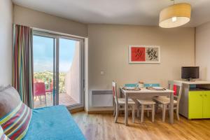 a living room with a table and chairs and a window at Le Murmure pieds dans l'eau in La Grande Motte
