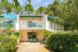 a house with a balcony and tables and chairs at Domaine de Pinsolle in Soustons