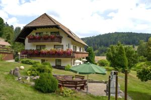 a house with a table and an umbrella in front of it at Haus Am Kaltenbach in Enzklösterle