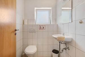 a white bathroom with a toilet and a sink at Ferienwohnungen große Albferien in Heroldstatt +27 photos