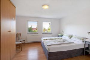 a bedroom with a bed and a desk and two windows at Ferienwohnungen große Albferien in Heroldstatt
