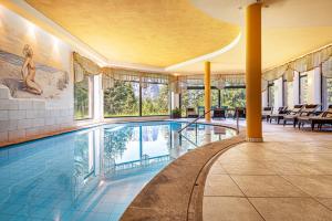a swimming pool in a building with windows and a pool at Sabina Dolomites Schlern in Alpe di Siusi