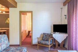 a living room with a television and a table and a chair at Sabina Dolomites Schlern in Alpe di Siusi