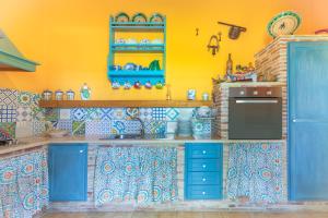 a kitchen with blue cabinets and a yellow wall at Casale siculo in Avola +15 photos