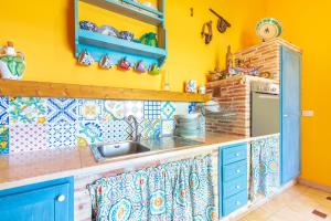 a yellow kitchen with blue cabinets and a sink at Casale siculo in Avola