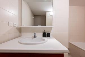 a bathroom with a white sink and a mirror at Valloire - Appartement avec piscine in Valloire +15 photos
