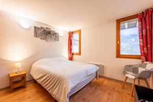 a bedroom with a bed and a chair and a window at Valloire - Appartement avec piscine in Valloire