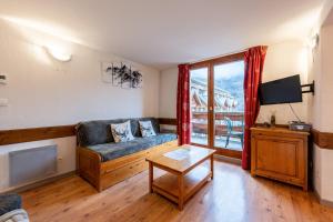 a living room with a couch and a tv at Valloire - Appartement avec piscine in Valloire