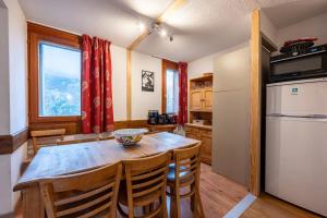 a kitchen with a wooden table and a refrigerator at Valloire - Appartement avec piscine in Valloire