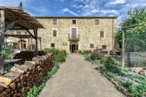 a large stone building with a bunch of logs at Can Casadellà in Serra de Daró