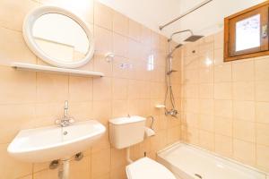 a bathroom with a sink and a toilet and a mirror at Arianna apartment 14 in Paleokastritsa +18 photos