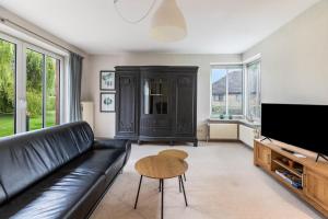 a living room with a black leather couch and a table at Ferienhaus Sprante in Brunsbüttel