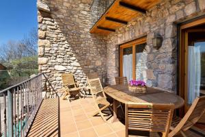 a patio with a wooden table and chairs on a balcony at Mas Cal Gintó in Das +29 photos