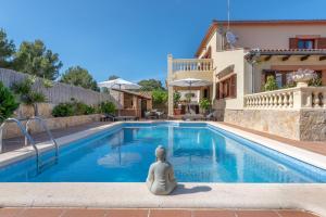 a villa with a meditating woman sitting next to a swimming pool at Villa Manrique in Cala Ratjada