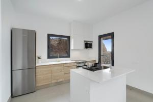 a white kitchen with a stainless steel refrigerator at Yucas Villa 17 in San Bartolomé