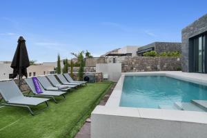 a row of lounge chairs next to a swimming pool at Yucas Villa 17 in San Bartolomé