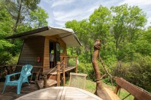 a cabin with a wooden deck with a blue chair at la pêcherie in Malbosc