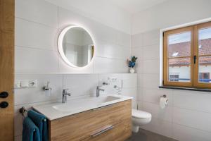 a bathroom with a sink and a toilet and a mirror at Ferienwohnung Maria in Gilching +17 photos