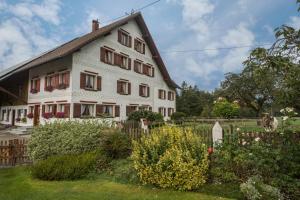 a large white house with a fence and flowers at Ferienhof Wetzel Fewo 1 in Hergensweiler