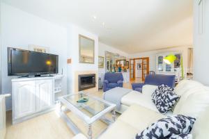 a living room with a white couch and a tv at La Vinya del Beato 1950 in Port de Pollensa