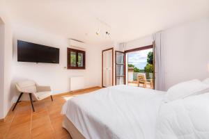 a white bedroom with a bed and a tv at Villa Font de sa Cala in Font de Sa Cala +27 photos