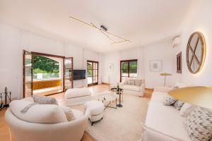 a living room with white furniture and a tv at Villa Font de sa Cala in Font de Sa Cala