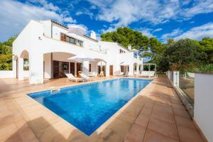 a villa with a swimming pool in front of a house at Villa Font de sa Cala in Font de Sa Cala