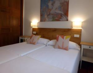 two beds in a hotel room with white sheets at Casa Rural Fuentebuena in Matabuena