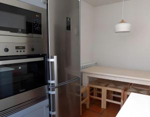 a kitchen with a stainless steel refrigerator and a table at Casa Rural Fuentebuena in Matabuena