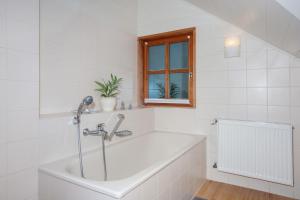 a white bathroom with a tub and a window at Ferienwohnungen Annamaria in Leutkirch im Allgäu +49 photos