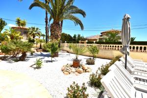 a garden with palm trees and a white bench at Villa Cucarres in Calpe