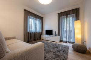 a living room with a couch and a tv and two windows at Plose 35 in Bressanone
