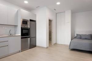 a kitchen and a bedroom with a bed and a microwave at Apartamentos Sealmar Moliere in Málaga
