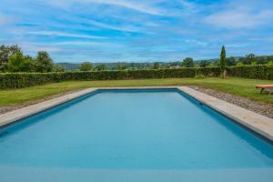 a blue swimming pool in a yard with a bench at Le Bel Prat in Domme