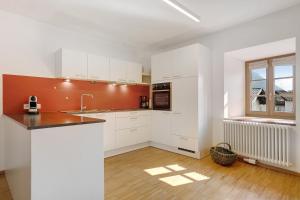 a kitchen with white cabinets and an orange wall at Appartement Wielander A Ost in Laces +9 photos