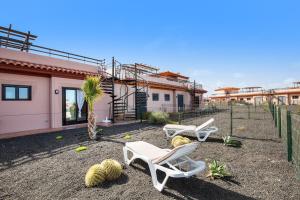 two chairs and cacti in a yard with a house at Sunny Home in Lajares