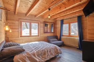 a bedroom in a log cabin with a bed and a chair at L'auberge du Bati in Besse