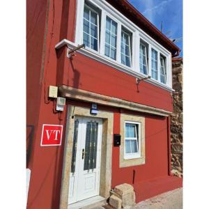 a red house with a white door and windows at Meraki in Finisterre