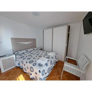 a small bedroom with a bed and a chair at Meraki in Finisterre
