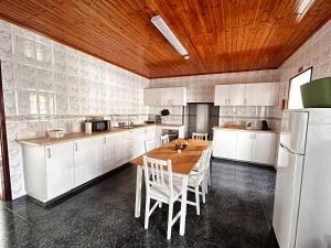 a kitchen with white cabinets and a wooden ceiling at Ocidente House 2 in Santa Cruz das Flores