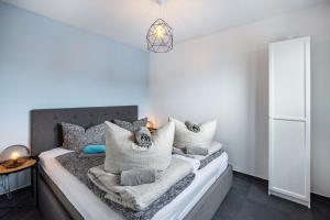 a bedroom with a bed with grey and white pillows at Ferienhaus Sonnenwind Hainer See Eg in Neukieritzsch