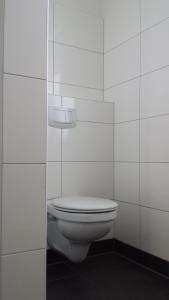 a white toilet in a white tiled bathroom at Ferienwohnung Birkenhof Alfsee in Rieste