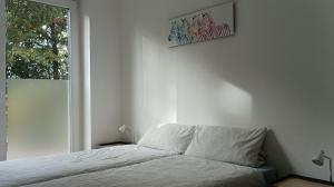 a white bedroom with a bed and a window at Ferienwohnung Birkenhof Alfsee in Rieste