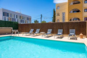a swimming pool with chairs and a table and a building at Villa Paca in Cala Ratjada