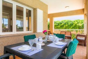 a dining table with green chairs and a black table at Villa Paca in Cala Ratjada
