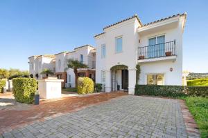 a large white house with a brick driveway at Arcos golf Adosado 2 dormitorios in Arcos de la Frontera
